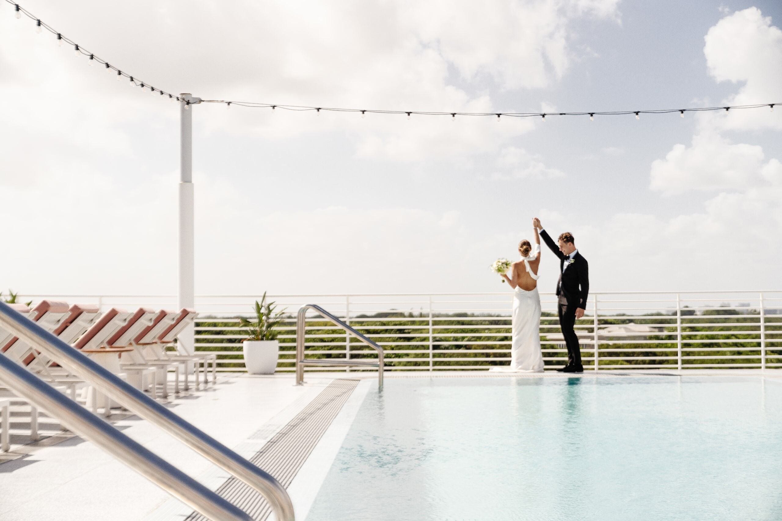 couple dancing by the pool in their wedding dress and suit